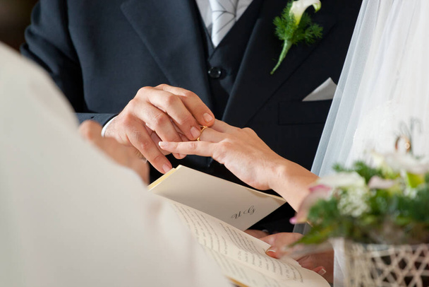 キリスト教の結婚式で花嫁の指に結婚指輪を置くグロム - 写真・画像