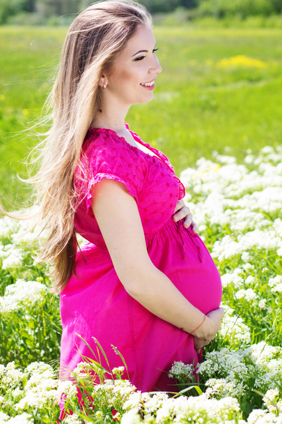 Happy pregnant woman sitting in white flowers - Zdjęcie, obraz