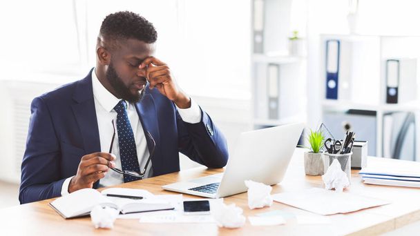 Problémy v práci. Rozrušený africký americký podnikatel si masíruje nos mostem s brýlemi v ruce, kopíruje prostor - Fotografie, Obrázek