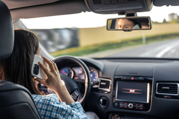 Bizneswoman prowadzi i rozmawia przez telefon. Młoda kobieta rozmawiająca przez telefon podczas jazdy samochodem. - Zdjęcie, obraz