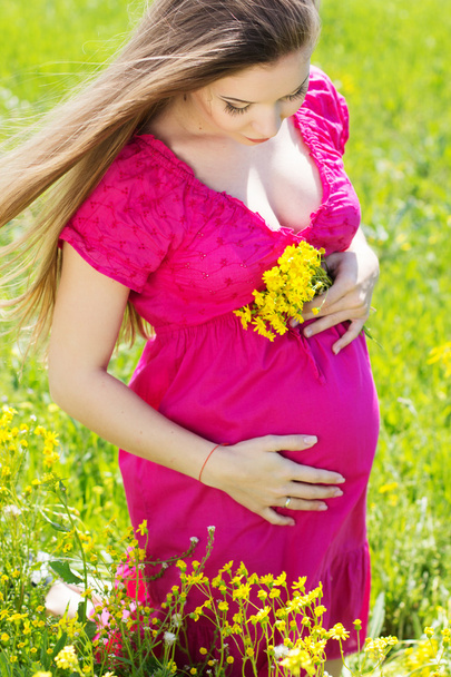 Felice donna incinta seduta in fiori gialli
 - Foto, immagini