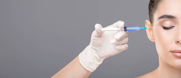 A woman is receiving a filler injection from a specialized doctor in a medical setting. The doctor is carefully administering the injection to the woman face, copy space - Photo, Image
