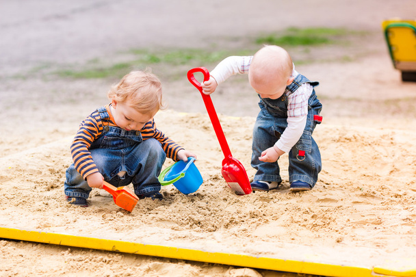 Two baby boys playing with sand - Photo, image