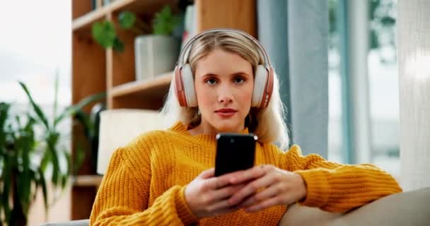 Lány, arc és fejhallgató telefonnal a kanapén audio streaming, közösségi média tekercs vagy hallgat podcast. Nő, személy és portré okostelefonnal a kanapén pihenni, könyv vagy boldog rádióval. - Felvétel, videó