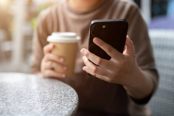 Oříznutý obraz ženy, která používá smartphone, popíjí kávu, sedí u venkovního stolu kavárny ve městě. koncepce lidí a bezdrátových technologií - Fotografie, Obrázek