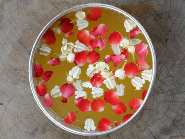 Κλείστε ένα ροδοπέταλα με λουλούδια γιασεμιού σε ένα μεγάλο ασημένιο μπολ με νερό για το μπάνιο του Βούδα. για το φεστιβάλ songkran ή το Thai New Year - Φωτογραφία, εικόνα