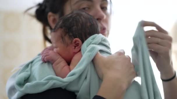 Matka jemně drží své novorozeně zabalené v měkkém ručníku po koupeli, ukazuje okamžik péče, teplo, a lepení, něha a pečující aspekty rodičovství - Záběry, video