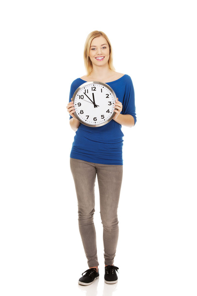 Young woman holding a clock. - Фото, зображення