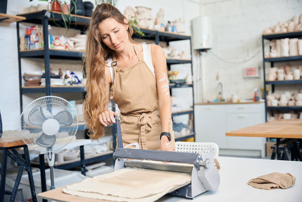 Орієнтована жінка використовує плиту роблячи саморобну кераміку у своїй творчій студії - Фото, зображення