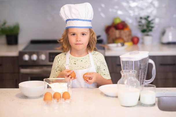 Kinderkoch kochen mit Eiern. Kinderkoch kochen Kochkunst. Kinder kochen. Junge mit Schürze und Kochmütze bereitet in der Küche eine gesunde Mahlzeit zu. Kochprozess - Foto, Bild