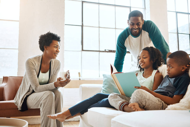 Familia negra, libro y niños con lectura en el sofá con sonrisa, cuidado y aprendizaje de la lengua en casa. Padres africanos, personas y narración de historias para la conexión, la vinculación y relajarse en pijamas en el sofá. - Foto, Imagen