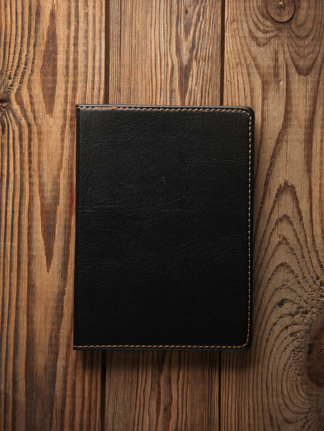 Quaderno con copertina in pelle nera su fondo legno - Foto, immagini