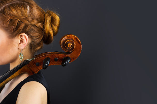 Μια νεαρή κοπέλα παίζει το βιολοντσέλο στο σκοτάδι. Τα χέρια για τσέλο - Φωτογραφία, εικόνα