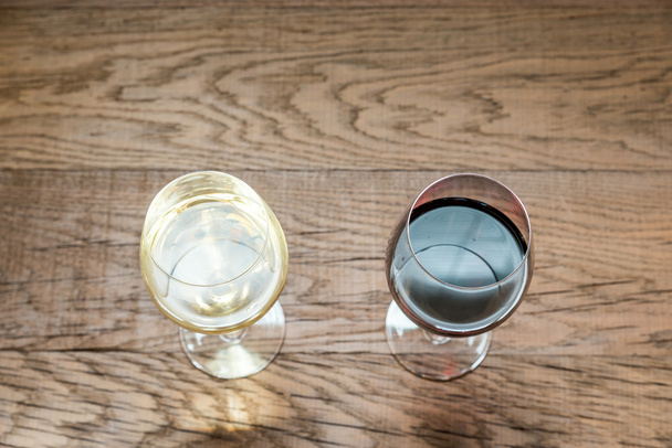 赤と白の木製の背景にワインのグラス - 写真・画像