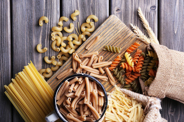 Different types of pasta in containers on wooden background - Fotoğraf, Görsel