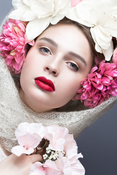 Belle fille dans un foulard dans le style russe, avec de grandes fleurs sur la tête et les lèvres rouges. Beauté visage
. - Photo, image