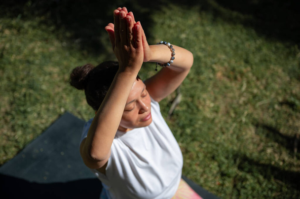 Eine Frau nimmt an einer achtsamen Yoga-Stunde im Freien teil und konzentriert sich an einem sonnigen Tag auf Entspannung und innere Ruhe. - Foto, Bild