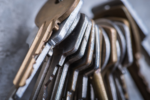 Купка старих зношених ключів на сірій бетонній стіні
 - Фото, зображення