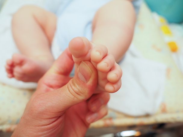 Baby receiving foot massage after diaper change with a thumb - Zdjęcie, obraz