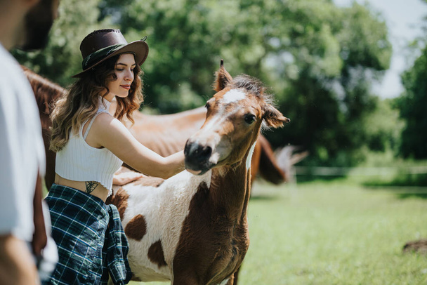 Jeune femme s'amusant au ranch, caressant un cheval et profitant d'une journée ensoleillée en plein air dans la nature. - Photo, image
