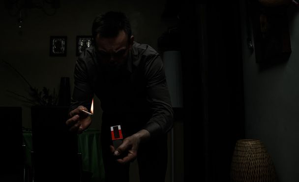 Людина, що тримає палаючу сірникову стрічку в темній кімнаті через відключення електроенергії
 - Фото, зображення