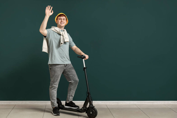 Giovane uomo con moderna scossa elettrica scooter vicino parete verde - Foto, immagini