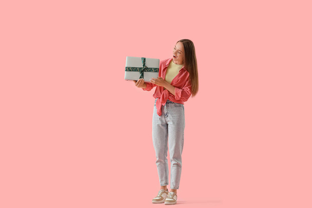 Šťastná mladá žena s dárkem notebook na růžovém pozadí - Fotografie, Obrázek