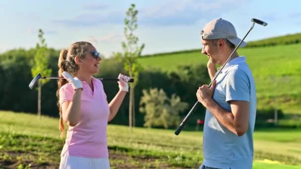 Un hombre y una mujer chocan los cinco después de jugar al golf en un día soleado - Imágenes, Vídeo