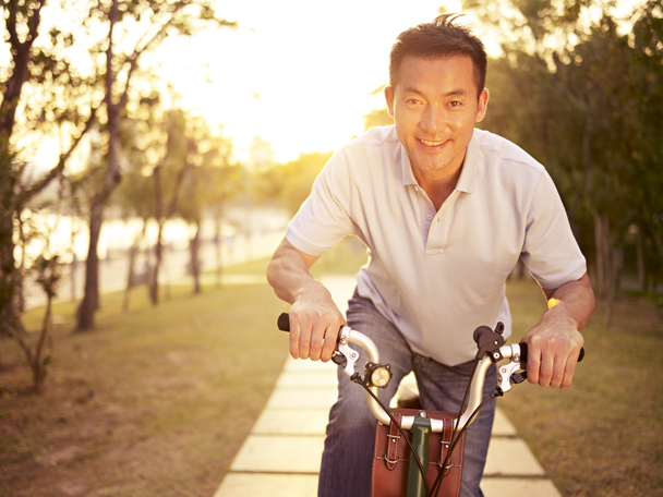 азіатський чоловік їде на велосипеді на відкритому повітрі на заході сонця
 - Фото, зображення