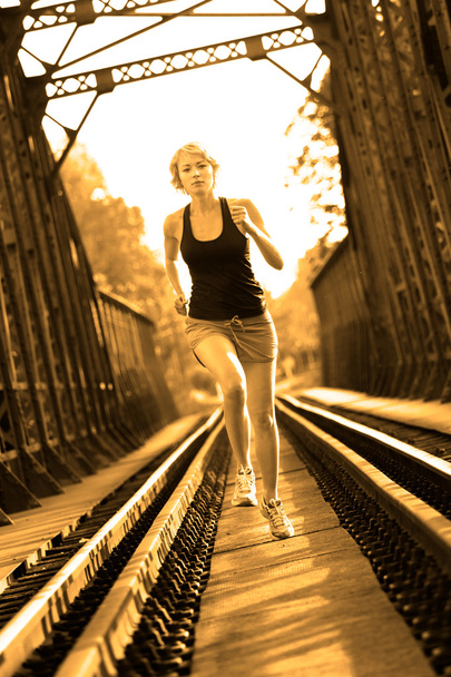 Atleta femenina activa corriendo en pistas ferroviarias
. - Foto, Imagen