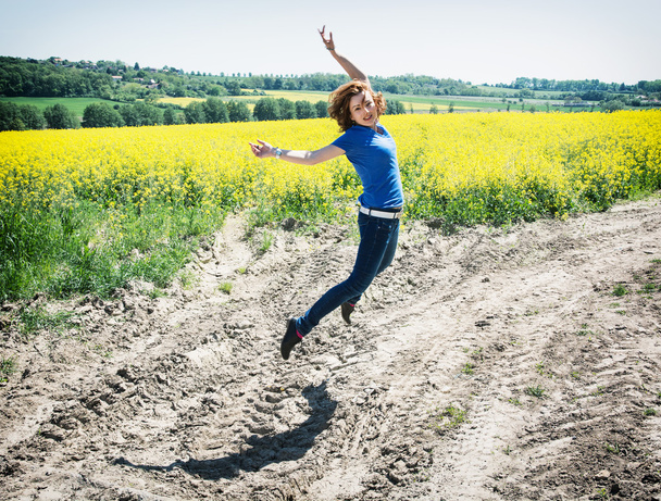 Positiivinen nuori nainen hyppii rypsipellolla
 - Valokuva, kuva