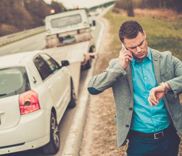 Hombre llamando mientras la grúa recoge su coche roto
  - Foto, imagen