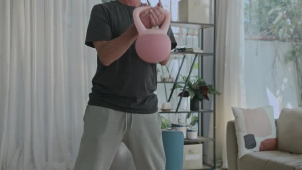 Kallista kuvaa valkoihoisesta keski-ikäisestä miehestä nostamassa käsipainoja harjoitellessaan kotona. - Materiaali, video