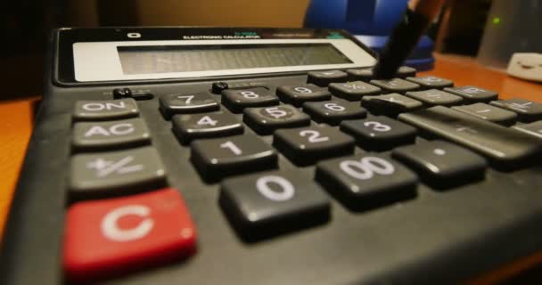 Een close-up shot van een boekhouder invoeren getallen op een rekenmachine met een potlood. - Video