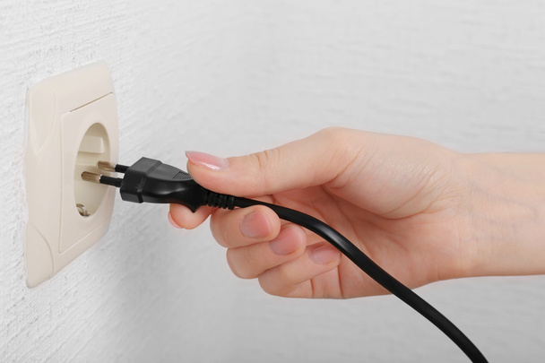 Hand putting plug in electricity socket close up - Foto, Imagem