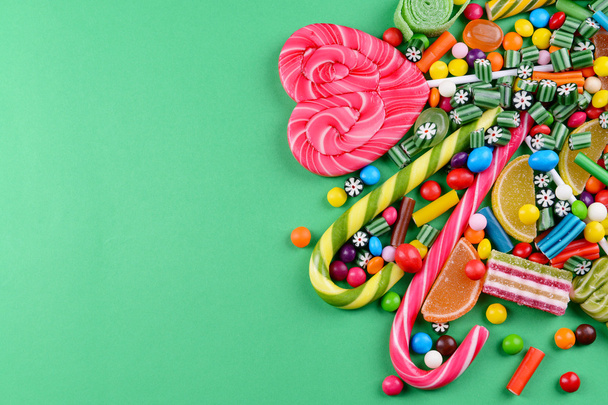 Colorful candies on green background - 写真・画像