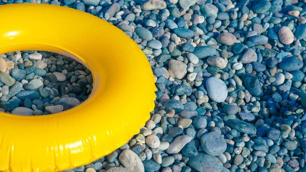 círculo de natación amarillo en la orilla del mar guijarro. - Foto, Imagen