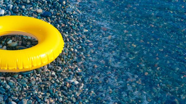 círculo de natação amarelo no litoral de seixos. - Foto, Imagem