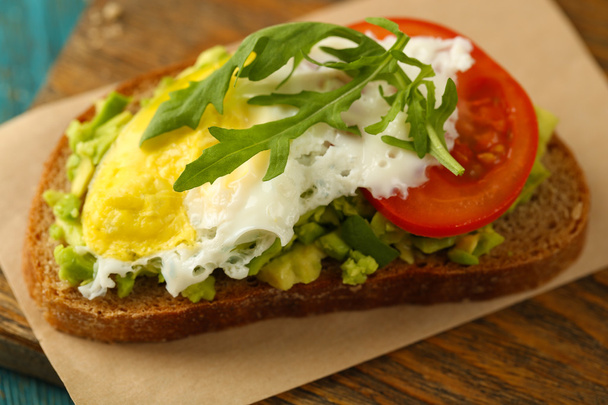 Tasty sandwich with egg, avocado and vegetables on wooden background - Photo, Image