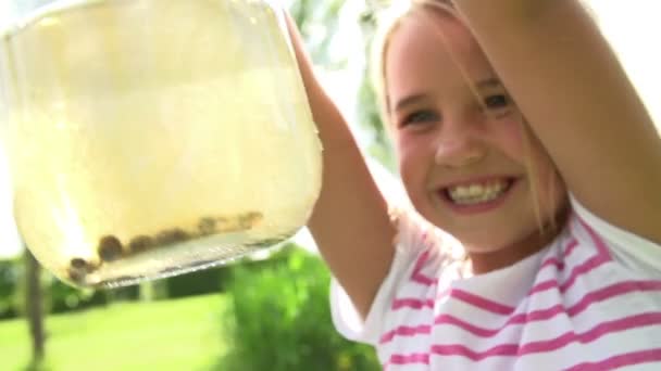 Girl holding glass with tadpoles - Filmati, video