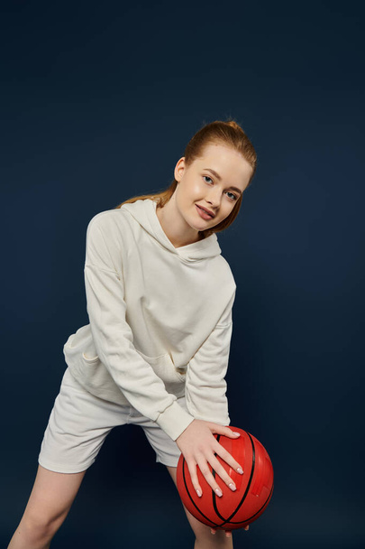 Mooie vrouw in witte kleding met een levendige rode basketbal. - Foto, afbeelding