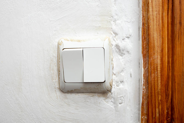 Vuile lichtschakelaar op wit beschilderde muurcement textuur, close-up  - Foto, afbeelding