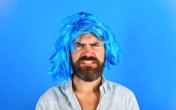 Homme en colère avec barbe et moustache en perruque bleue. Concept de mode. Beau mâle en perruque colorée. Publicité chez le coiffeur. Un mec élégant aux cheveux bleus. C'est parti. Portrait de hipster barbu en péruke - Photo, image