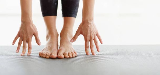 Kırpılmış kadın, bir stüdyoda elleri yoga minderinde ayaklarına değen bir esneme egzersizi yaparken görülüyor. Bir sabah rutini sırasında esneklik ve denge üzerine odaklanılır, panorama, kopyalama alanı - Fotoğraf, Görsel
