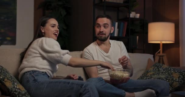 Nappali egyetlen fényforrás jön a TV képernyőjén fiatal nő és férfi ül egymás mellett a kanapén elmerülve a filmben időnként megállás dobált popcorn egymás ellen és kuncogott ellenőrizhetetlenül. - Felvétel, videó