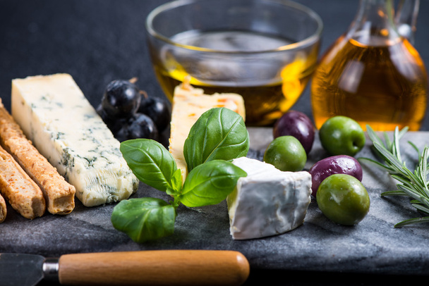 Selezione di formaggi in stile tapas con olive, uva ed erbe aromatiche
 - Foto, immagini