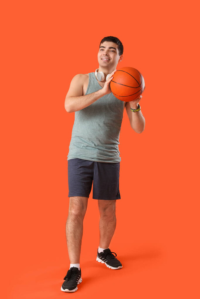 Sportowy młody człowiek z piłką na pomarańczowym tle - Zdjęcie, obraz