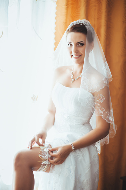Bride getting ready. beautiful bride in white wedding dress with hairstyle and bright makeup. Happy sexy girl waiting for groom. Romantic lady in bridal dress have final preparation for wedding - Foto, afbeelding