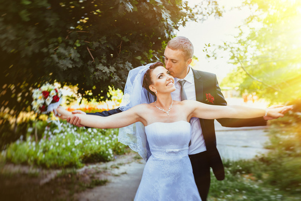Bride and Groom at wedding Day walking Outdoors on spring nature. Bridal couple, Happy Newlywed woman and man embracing in green park. Loving wedding couple outdoor. - Photo, image