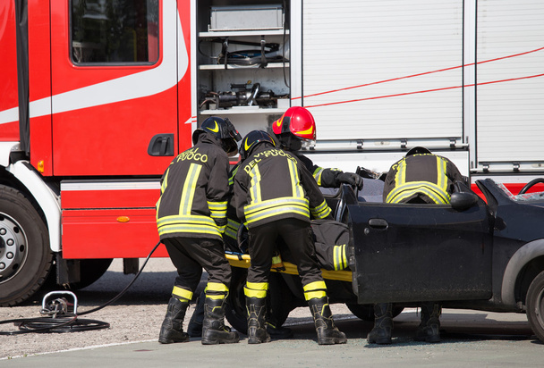 Palomiehet vetävät auton kilvet haavoittuneina liikenneonnettomuuden jälkeen
 - Valokuva, kuva